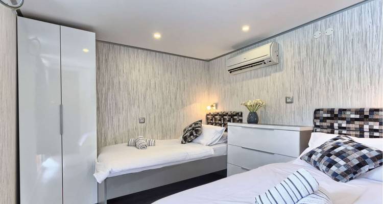 Twin-bed cruise cabin with modern décor, air-conditioning, and bright lighting.