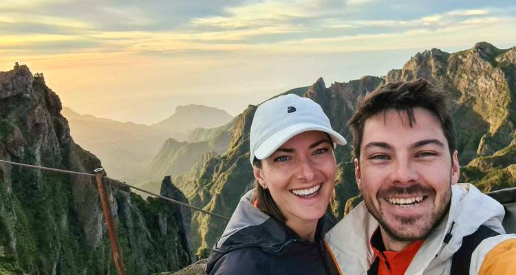Couple heureux prenant un selfie avec des pics montagneux déchiquetés et un ciel de coucher de soleil coloré en arrière-plan