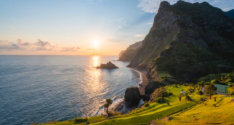 Coucher de soleil doré sur une côte verte escarpée et les eaux calmes de l'Atlantique