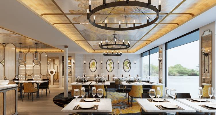 Un élégant restaurant avec vue sur le fleuve dispose d'un plafond voûté orné de fresques, de lustres circulaires et de tables joliment dressées.