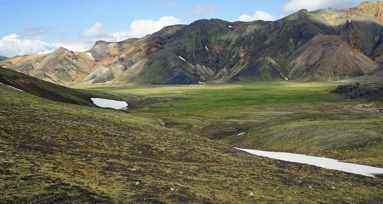 Farbenfrohe Rhyolith-Berge und grünes Tal von Landmannalaugar mit verbleibenden Schneeflecken.