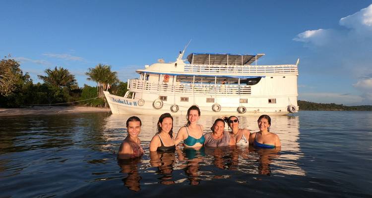 Grupo de seis mujeres disfrutando de un baño junto a un crucero fluvial blanco en el Amazonas.