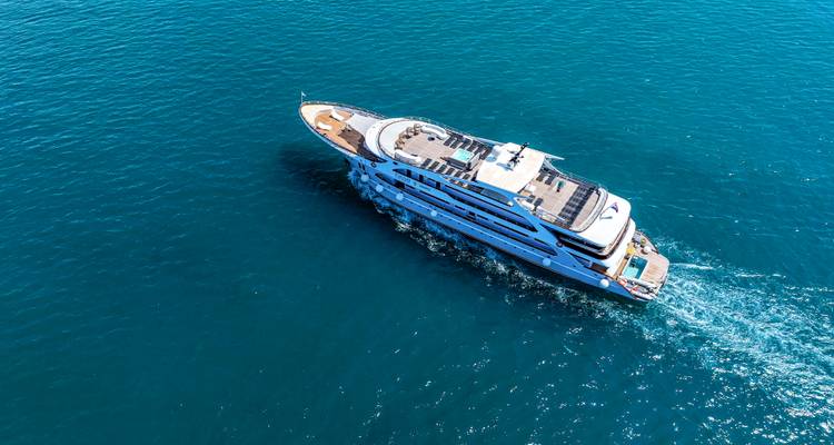 Aerial view of a sleek white yacht cruising through deep blue Adriatic waters.