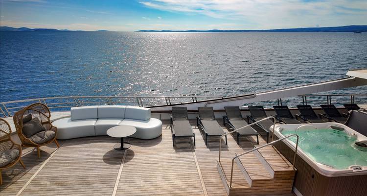 Sundeck seating with sea horizon and jacuzzi on luxury yacht.