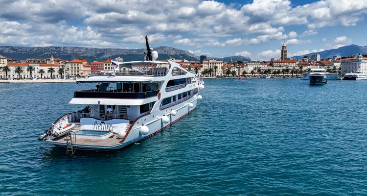 Rear view of yacht approaching Split harbour under partly cloudy sky.