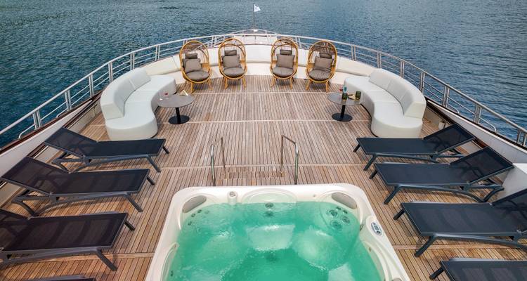 Close-up of bubbling jacuzzi and loungers on yacht’s front deck.