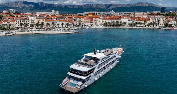 Yacht sailing off Split waterfront with red-roofed old town backdrop.