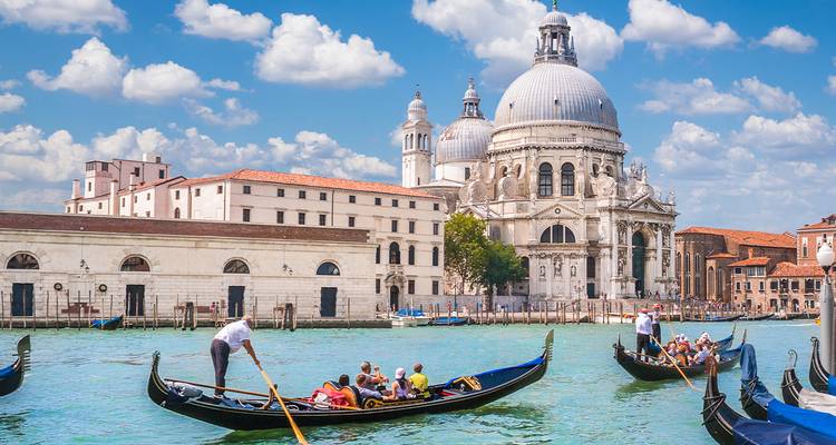 Les gondoliers naviguent sur les canaux émeraude en passant devant les dômes de la Basilique Sainte-Marie-de-la-Salute à Venise.