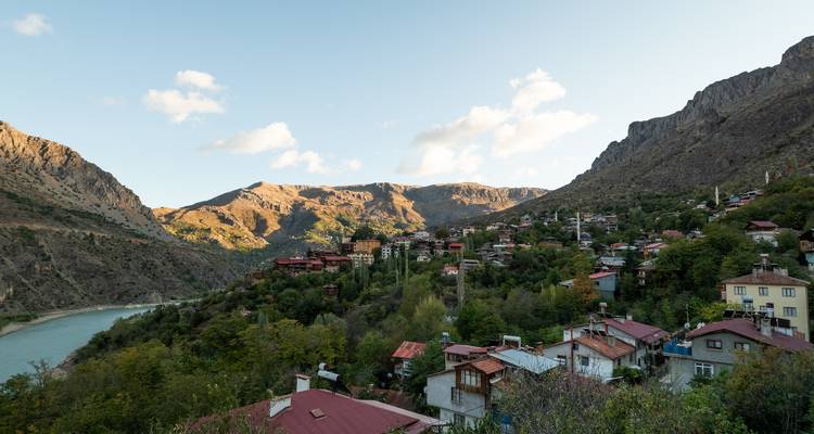 Charming riverside mountain village with terracotta roofs nestled among steep green slopes.