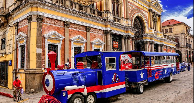 Colorful tourist road-train parked outside an ornate historic building in Quetzaltenango