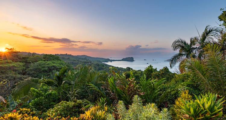 Un coucher de soleil orange colore le ciel au-dessus de la jungle verdoyante et des baies lointaines sur la côte Pacifique du Costa Rica