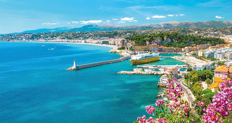 Panoramic view of a turquoise bay, city of Nice, cliffs and a lighthouse along the French Riviera