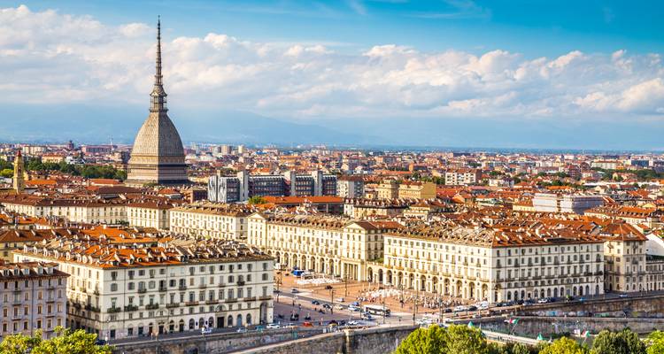 Skyline of Turin featuring the distinctive Mole Antonelliana rising above terracotta rooftops.