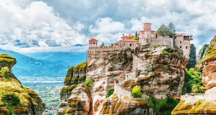 Monastère spectaculaire perché au sommet des imposants piliers rocheux de Meteora avec des montagnes enneigées au-delà.