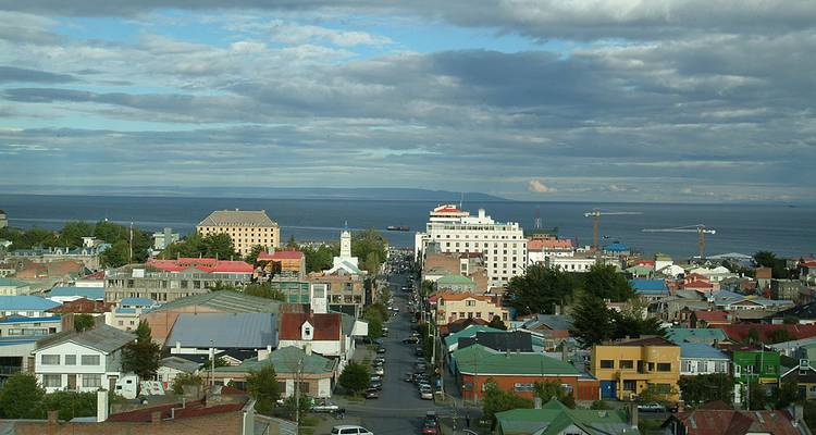 Panoramic view over colorful rooftops of Punta Arenas stretching toward the Strait of Magellan.
