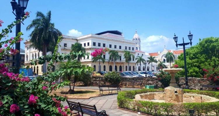 Place coloniale ensoleillée à Panama City avec des bougainvillées en fleur, des bancs, une fontaine et des bâtiments historiques blancs en arrière-plan