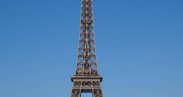 Close-up view of the Eiffel Tower’s lattice ironwork set against a flawless blue sky.