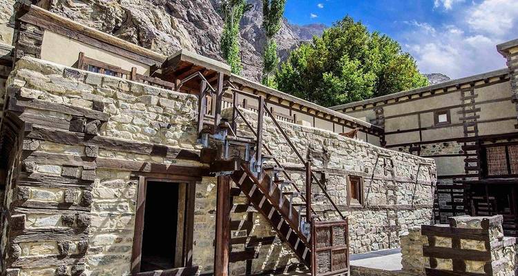 Muros de piedra rústica, escaleras de madera y el telón de fondo montañoso de la arquitectura de la fortaleza restaurada en el Valle de Shigar.
