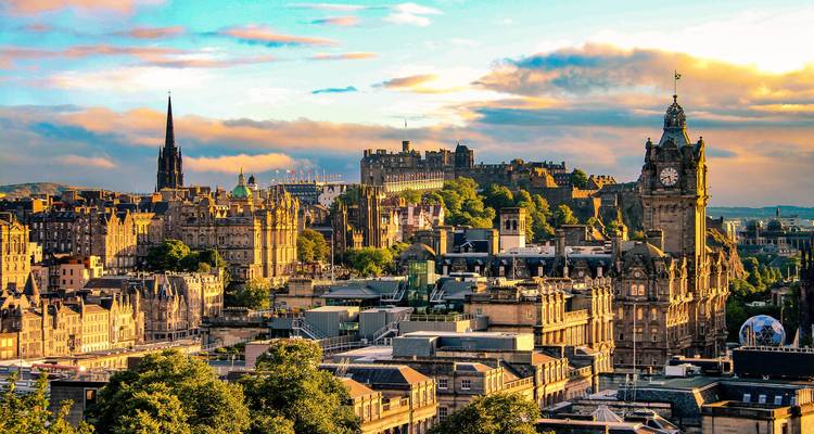 Vibrant Edinburgh skyline with castle and clock tower glowing under dramatic evening clouds