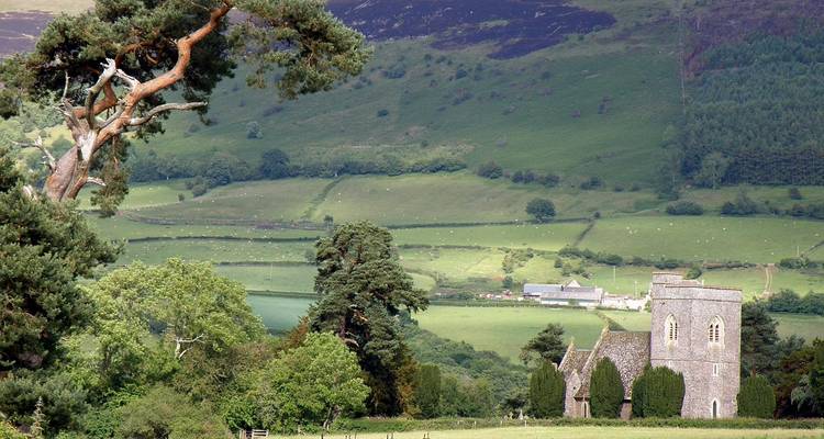 Église en pierre nichée dans la verdoyante campagne galloise avec un paysage de collines ondulantes en arrière-plan