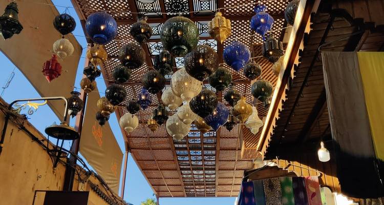 Des lanternes marocaines colorées suspendues à un toit en treillis de bois dans une ruelle de souk
