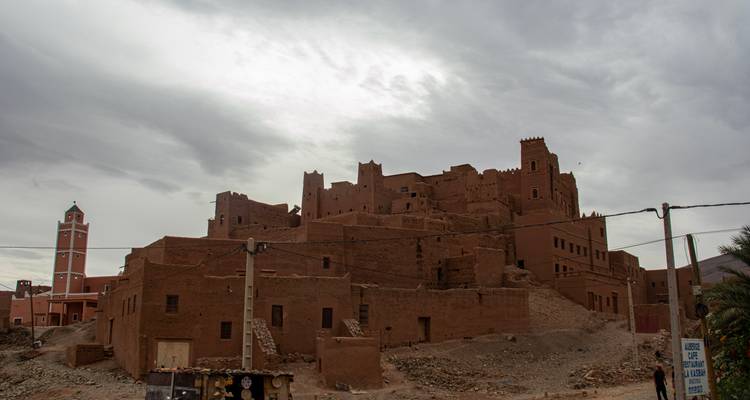 Vue nuageuse de la kasbah en terre crue d'Aït Benhaddou avec des poteaux d'utilité publique au premier plan