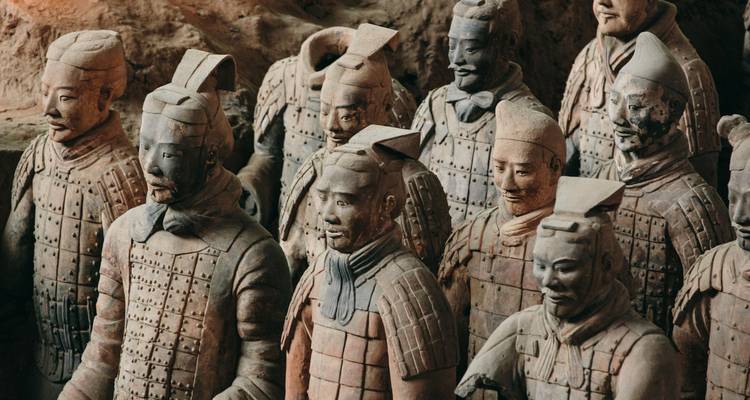 Reihe lebensgroßer Terrakotta-Krieger-Statuen, die in Lehmgruben stehen und detaillierte Rüstungen sowie gelassene Gesichtsausdrücke aufweisen
