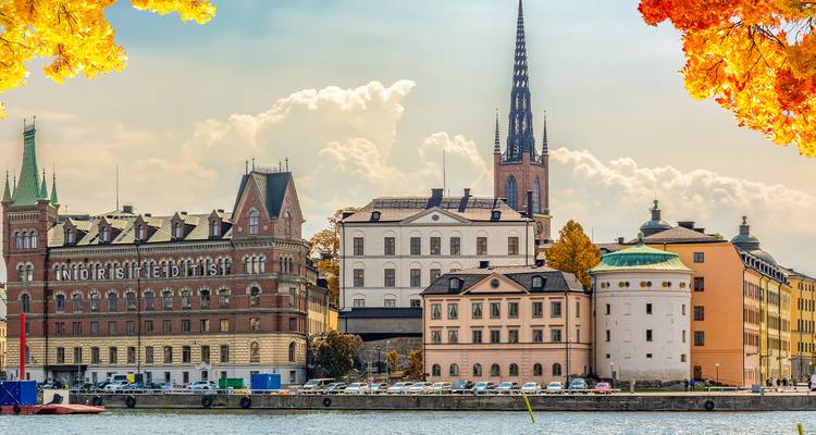 Autumn-framed skyline of Stockholm’s historic buildings and church spire viewed across the water.