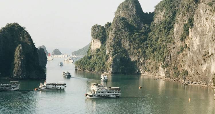 Kreuzfahrtschiffe gleiten zwischen aufragenden Kalksteinfelsen auf den ruhigen smaragdgrünen Gewässern der Halong-Bucht