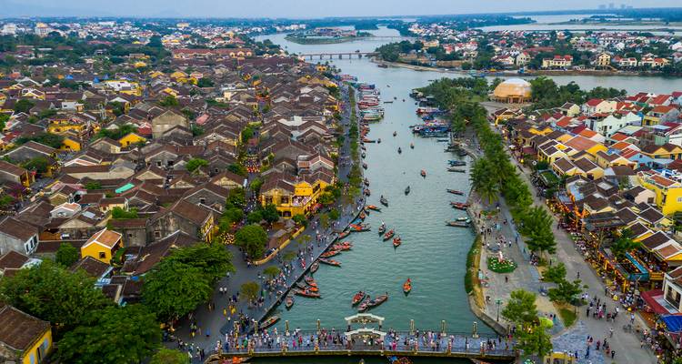 Luftaufnahme der Dächer mit Ziegeln der Altstadt von Hoi An, die einen belebten Fluss mit farbenfrohen Booten säumen