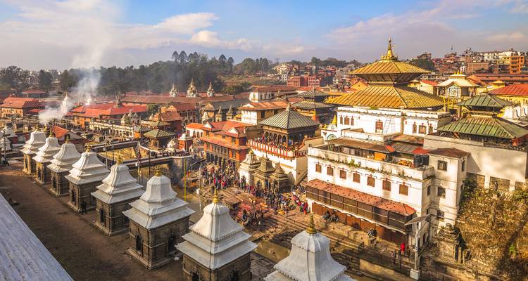Vista panorámica de pájaro del complejo del templo de Pashupatinath con ghats funerarios y humo ascendente.