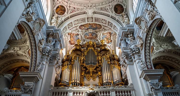 Magnifique orgue de tuyauterie baroque richement décoré à l'intérieur d'une cathédrale blanc pur avec des fresques de plafond ornées.