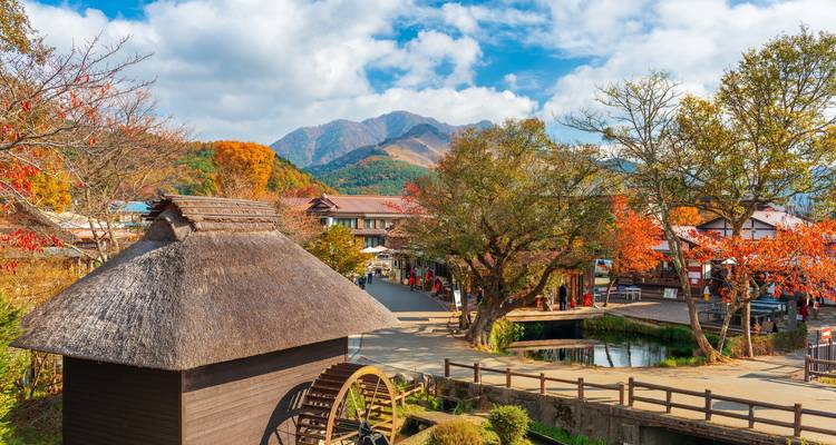 Picturesque traditional village with waterwheel and autumn colors backed by mountains.