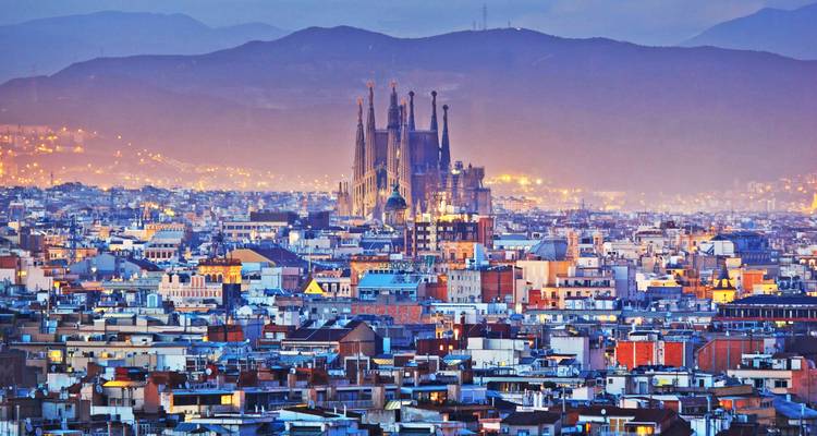 Dusk skyline of Barcelona dominated by the Sagrada Família with mountains in the background