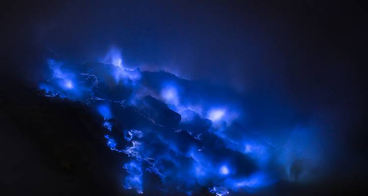 Les mystérieuses flammes bleues du volcan Ijen brûlant la nuit dans une fumée tourbillonnante.