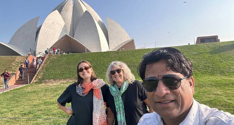 Selfie of three tourists with the Lotus Temple rising behind a grassy hill