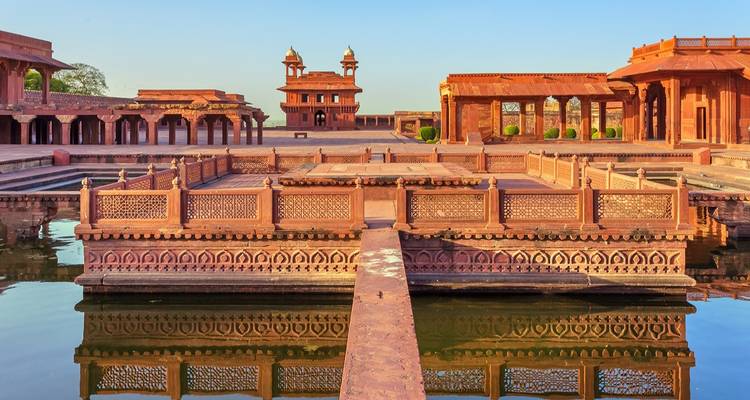 Symmetrical red-sandstone palace complex reflected in a rectangular pool at Fatehpur Sikri
