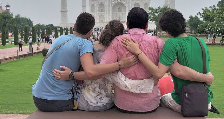 Vier Freunde, Arm in Arm verschlungen, bewundern das Taj Mahal über gepflegten Gärten hinweg
