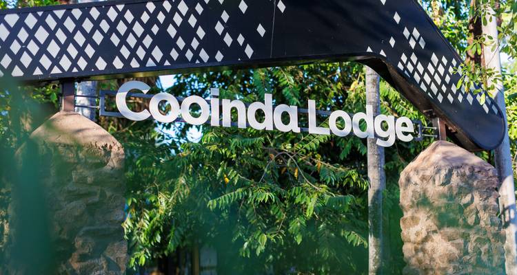 Eingangsschild der Cooinda Lodge, umgeben von üppiger tropischer Vegetation.