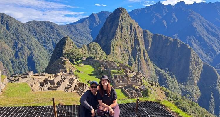 Deux voyageurs posent avec les terrasses emblématiques et les pics de Machu Picchu s'étendant derrière eux.