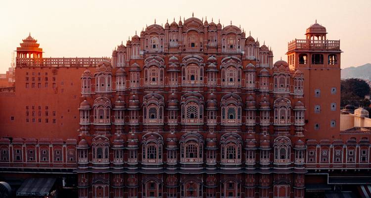 Fachada ornamentada de arenisca roja del Hawa Mahal de Jaipur brillando con la cálida luz del atardecer.