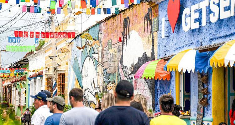 Tourists walk a colourful graffiti-lined street in Colombia festooned with paper flags.
