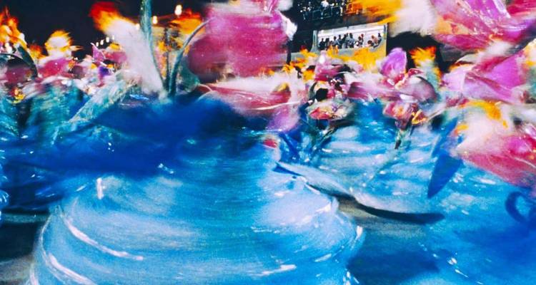 Foto con movimiento borroso de vibrantes bailarines de samba azul y rosa girando durante el desfile del Carnaval de Río por la noche.
