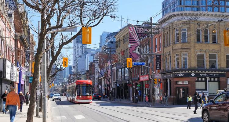 Rue du centre-ville de Toronto avec un tramway rouge, des bâtiments patrimoniaux et des gratte-ciel modernes.