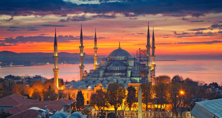 Mosquée emblématique aux six minarets élancés se découpant sur un ciel de coucher de soleil flamboyant dominant le Bosphore.