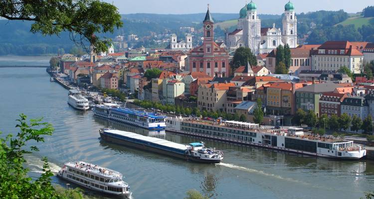 Panoramic view of Passau with colourful riverside houses, church towers and cruise ships navigating the Danube.