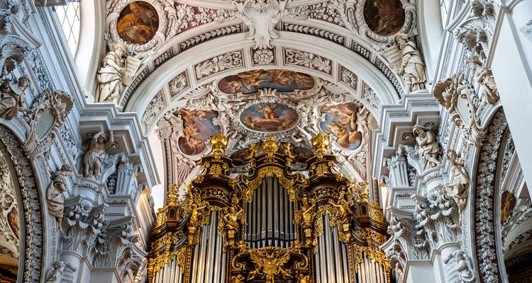 Ornate golden organ and frescoed ceiling inside the richly decorated Passau Cathedral.