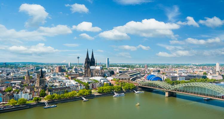 Large panorama aérienne de la ligne d'horizon de Cologne avec la cathédrale et le Rhin sous un ciel lumineux.