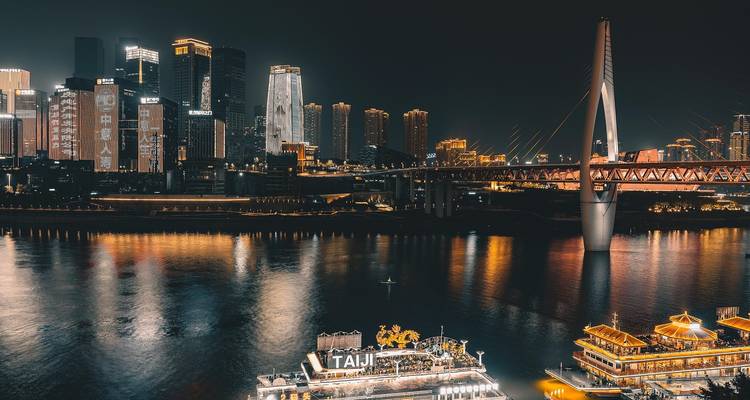 La ligne d'horizon illuminée de Chongqing et le pont scintillant sur le fleuve Yangtze la nuit.