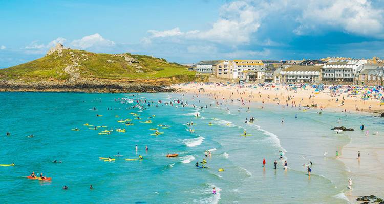 Plage de sable bondée avec des surfeurs et des baigneurs dans une ville balnéaire animée